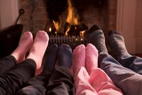 Photo shows the feet of a family in front of a fire