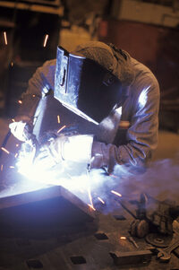 Photo shows a welder wearing protective clothing