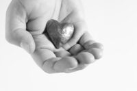Photo shows a hand holding a metal heart