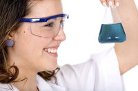 Photo shows a woman handling a chemical and wearing safety glasses