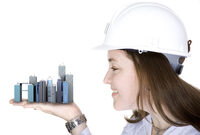 Photo shows a woman wearing a hard hat holding buildings in her hand