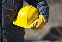Photo shows a construction worker holding a hard hat