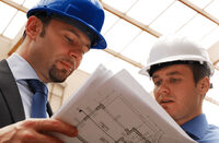 Photo shows two workers looking at blueprints